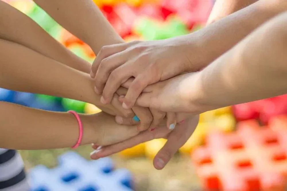 Mehrere Hände liegen übereinander, was Teamwork oder Zusammengehörigkeit symbolisiert