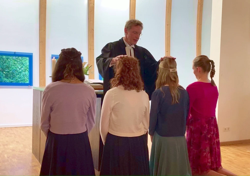 Ein Geistlicher legt vier jungen Frauen die Hände auf den Kopf