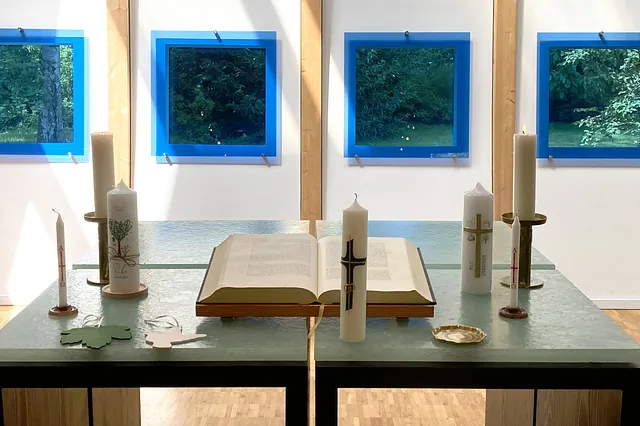 Ein Altar mit einer aufgeschlagenen Bibel, Kerzen und Blumen in einer Kirche
